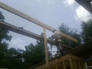 Carpenter setting a ridge beam over a new addition frame — Ice Dam Removal by Roofing Brothers in Iota