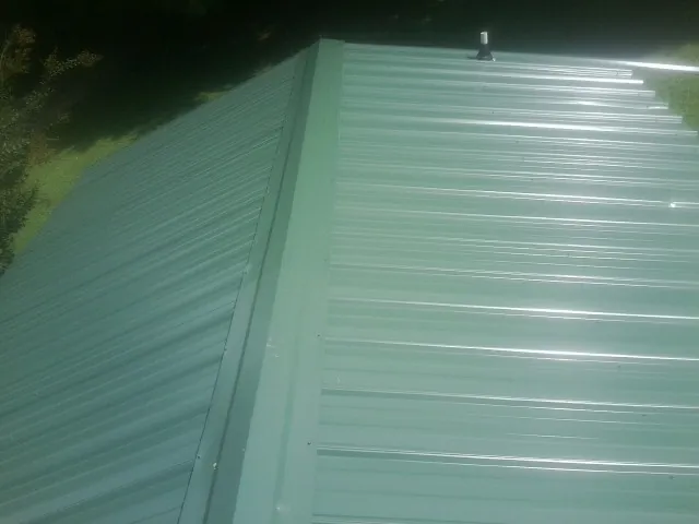 New green metal panels meeting at the ridge of a roof — Flat Roof Repair work by our crew in Iota