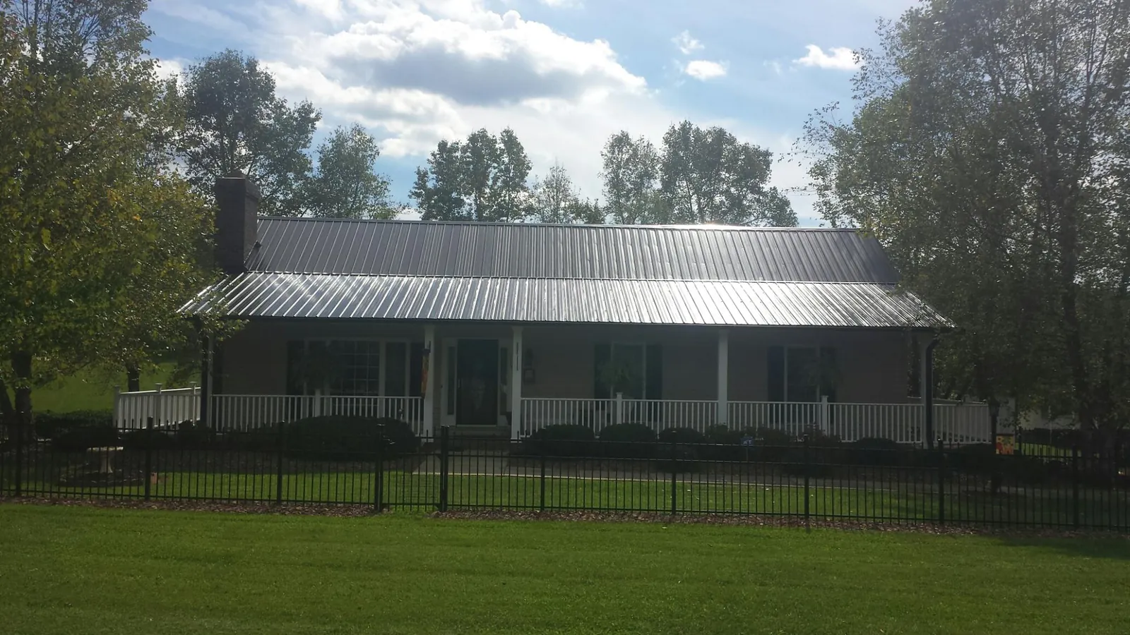 Gray metal roof on a brick ranch with a full width front porch — Gutter Guard Installation work by our crew in Iota