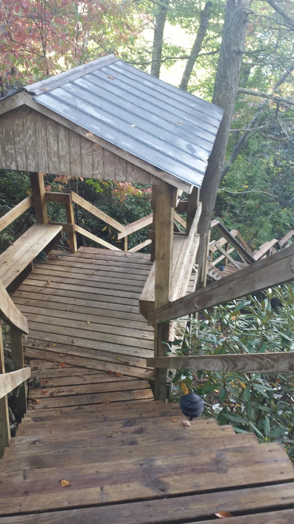 Metal roofed shelter over wooden steps on a wooded walkway — Skylight Repair & Installation work by our crew in Iota